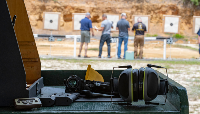 pistol on bench while competitors score targets